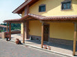 Portico in legno con tetto in tegole su casa gialla
