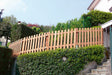 Recinzione in legno e siepe verde rigogliosa in un giardino esterno.