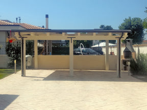 Struttura coperta da esterno con tettoia e zona barbecue in un patio pavimentato.