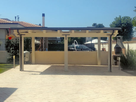 Struttura coperta da esterno con tettoia e zona barbecue in un patio pavimentato.