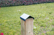 Copripilastro MINUTEX in acciaio verniciato grigio grafite su palo di legno in giardino