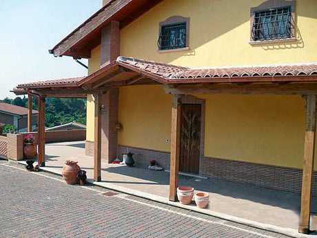 Portico in legno con tetto in tegole per casa gialla